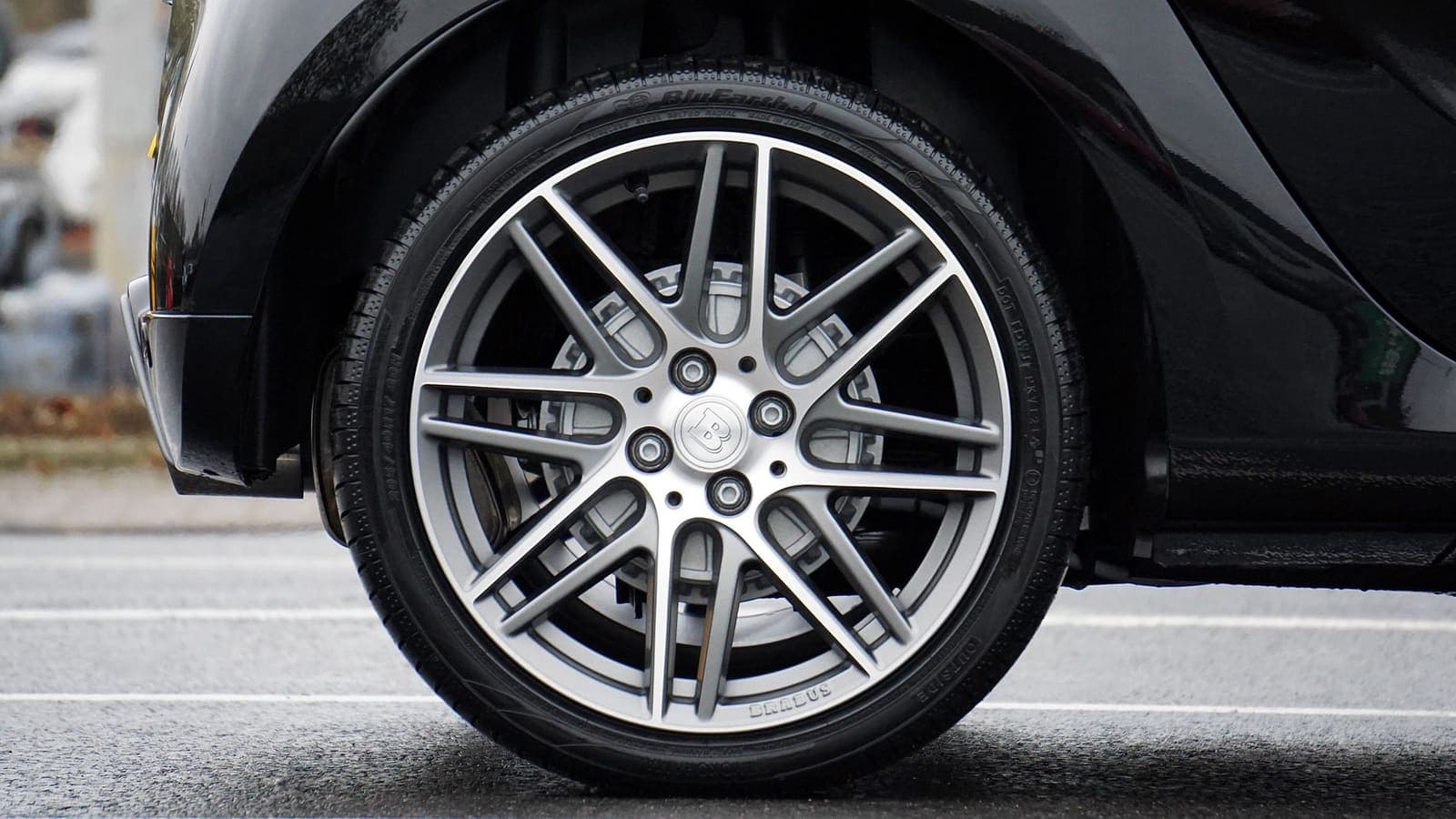 Lichtmetalen velg met band op een donkere personenauto, van opzij gezien